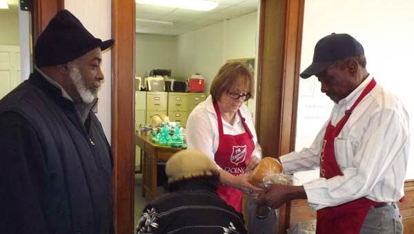 Wadell Lewis, left, looks on as G. Easter, Donna Saubier and Roosevelt Johnson gather some food in bags. -- Stephen H. Cowles | TIdewater News