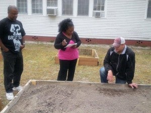 From left, Ricky Johnson and his wife, Rheila, and Chris Drake with Southampton County Cooperative Extension. Drake is demonstrating proper seed placement for kale in raised box gardens. -- SUBMITTED PHOTO