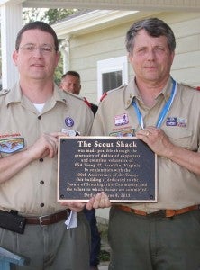 Scout leaders David Benton, left, and Tom Jones IV show the official plaque dedicating the new Troop 17 Scout Shack at Saturday’s ceremony. It states the building is dedicated to the future of Scouting, the community and the values to which scouts are committed.  -- DON BRIDGERS/TIDEWATER NEWS
