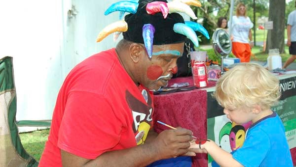 'Coach the Clown" paints a spider on the hand of Hayden Lee, 2, son of Mindy Lee of Courtland. -- MERLE MONAHAN/ CONTRIBUTING WRITER