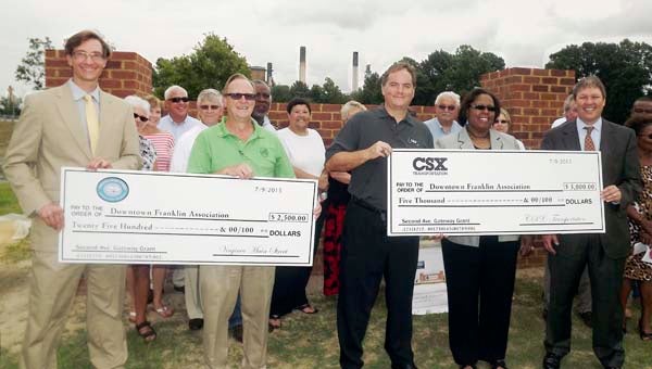 Brad Belo, left, and Dan Howe hold the $2,500 grant from the Virginia Main Street Program for the Second Avenue Gateway project, which is behind them. Presenting the $5,000, also to the Downtown Franklin Association for the sign, are David Farley of CSX Transportation, Franklin Mayor Raystine Johnson-Ashburn and Douglas Smith of Kaufman & Canoles. -- STEPHEN H. COWLES/TIDEWATER NEWS