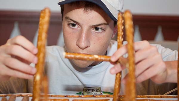 Justin Heiser of Courtland works on his part of building a model of the Alpengeist rollercoaster made out of the pretzels from Snyder's of Hanover. James Williams, his friend, also worked with him on the project. The recent contest was held at Busch Gardens in Williamsburg. -- SUBMITTED