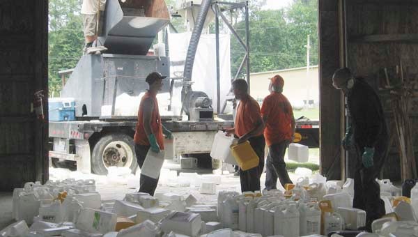 Southampton County Jail inmates on a work release program help throw empty and rinsed pesticide containers into a grinder at the fairgrounds. The granules will later be taken elsewhere for recycling into a number of new uses. -- STEPHEN H. COWLES/TIDEWATER NEWS