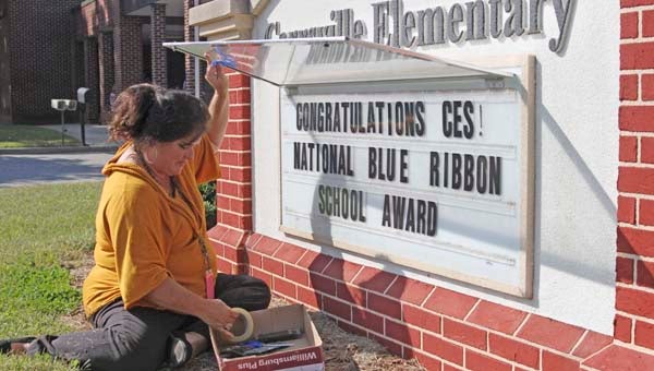 Assistant principal and reading specialist Tiffany Blatt works on the sign in front of the school. She is adding a blue ribbon. -- Cain Madden | Tidewater News