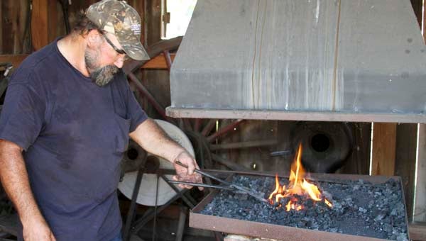 In the old blacksmith shop, Lesley Mosley demonstrates on the foundry how a Flesh fork is made. -- DON BRIDGERS | TIDEWATER NEWS