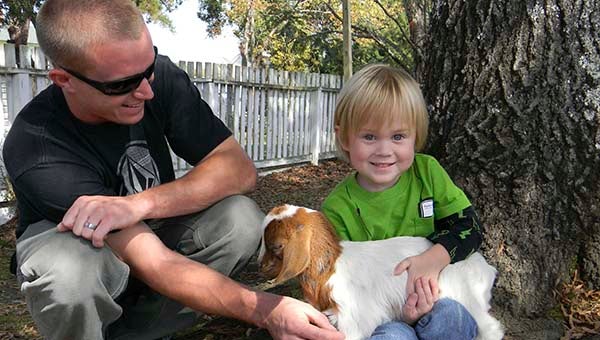 Trevor Kirste and his son, Neil, 3, of Branchville pet a 3-week-old goat at the last year’s PumpkinFest in Boykins. Event chairwoman Denise Byrum said there will be plenty for both children and adults at this year’s event. -- FILE PHOTO
