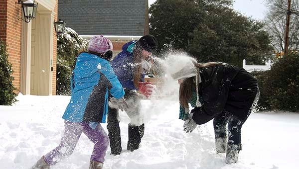 Helene Kimlick, 9, left, Paige Parker, 16, and Madalyn Kimlick, 17, have a snow fight i front of the Franklin Baptist Church. -- Cain Madden | Tidewater News