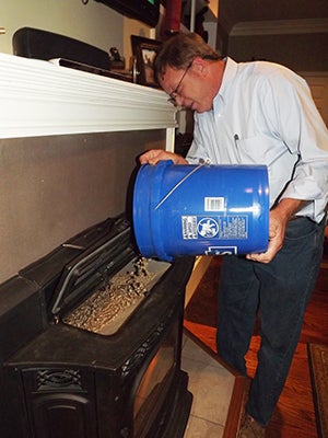 Julien Johnson, director of utilities for Southampton County, pours some of the first wood pellets made by Enviva into the stove at his home in the Holland Borough of Suffolk. The capsules were given to Johnson as a one-time only courtesy. Photo by Stephen H. Cowles