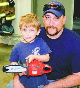 Mason Futrell, 3, and his father, Brian Futrell, of Courtland. Mason won a toy chain saw at the gun bash. -- Merle Monahan | Tidewater News