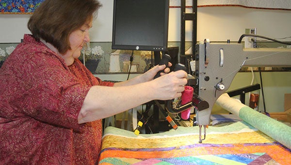 Louann Gram uses a long arm machine to stitch the shimmer pattern to its backing, which is always cotton. Gram said that customers who buy all fabrics from her qualify for a discount on both materials and use of the machine. -- Cain Madden | Tidewater News