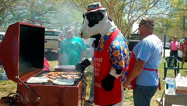 The Chick-Fil-A mascot from Suffolk joins Zuni Hunt Club members in cooking burgers. -- MERLE MONAHAN | TIDEWATER NEWS