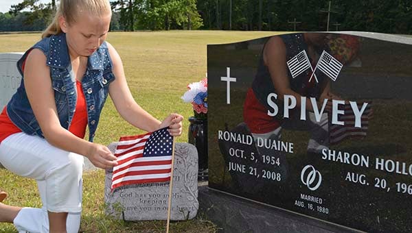 Ryleigh Skeeters, 12, places a flag at the graveside of Ronald D. Spivey. The Navy veteran is buried at Hollywood Cemetery in Newsoms. For Memorial Day weekend, Skeeters and members of the Newsoms Ruritan Club placed flags on the graves of approximately 114 other veterans. -- SUBMITTED | JOHN SKEETERS