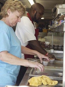 Debbie Livingston and Maurice Perry of Nixon’s Catering prepare cups of sauce for the barbecue. -- Stephen H. Cowles | Tidewater News