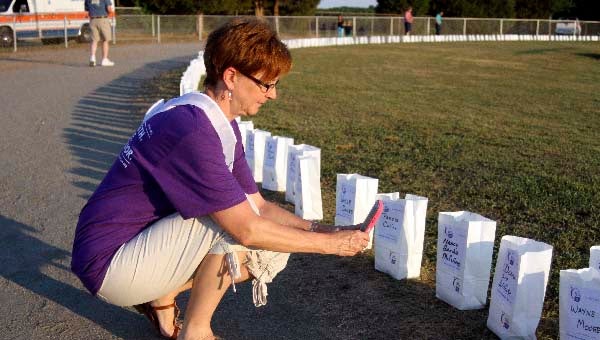Jeannette Everett, a survivor, takes a picture of Donna Lee Withers’ Luminaria. -- CAIN MADDEN | TIDEWATER NEWS