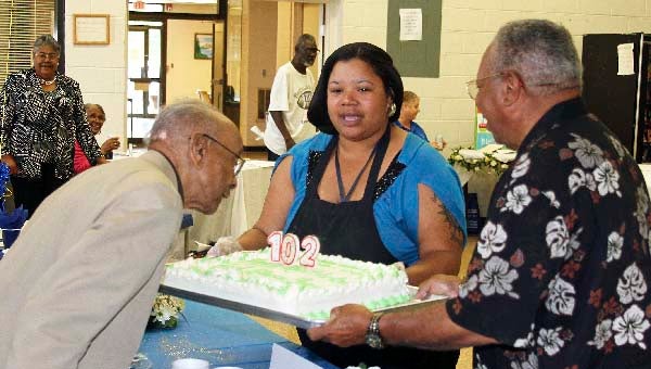 Benjamin “B.J.” Holland, left, blows out the candle on his cake. On Thursday he celebrated his 102 anniversary at the Martin Luther Community Center in Franklin. -- FRANK DAVIS | TIDEWATER NEWS
