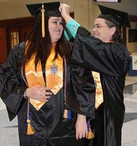 Christine Wells, right, helps her daughter, Amanda Douglas, adjust her cap as the two get prepared to graduate from Paul D. Camp Community College at the Regional Workforce Center. -- DON BRIDGERS | TIDEWATER NEWS