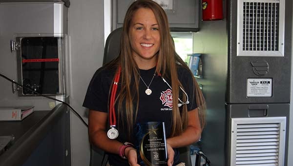 Sam White, a Hunterdale volunteer firefighter, holds her award for Outstanding Contribution to EMS by a High School Senior inside one of the station’s ambulances. -- CAIN MADDEN | TIDEWATER NEWS