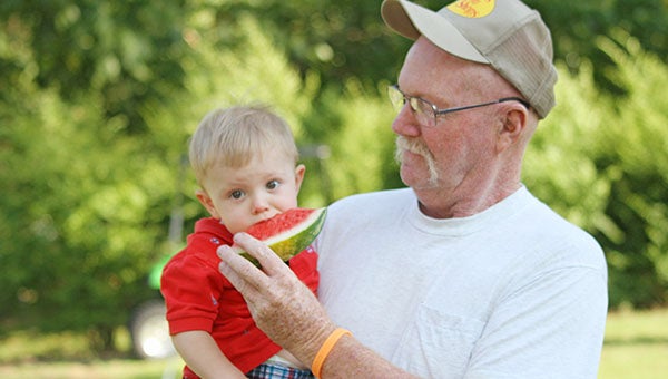 Briar Pruitt, 17 months, gladly takes a bite of watermelon from his grandfather Tommy Lowe of Ivor. The two were enjoying the celebration at the Newsoms Ruritan Club after the parade had gone through town.