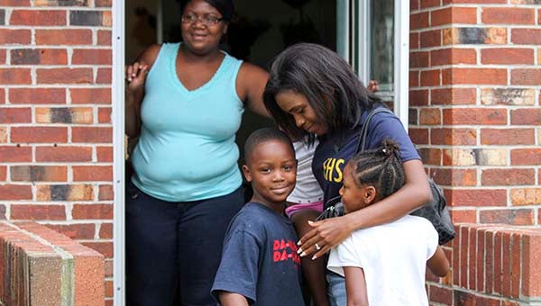 Takayah Brown, 2, Quayvion Brown, 7, and Takacia Brown, 5, come out to hug Twynnette Anderson, who now teaches at Franklin High School, but had taught music at the lower school. In the background is their mother Chaquana Brown. -- CAIN MADDEN | TIDEWATER NEWS