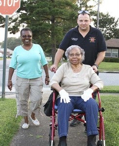 Jerry Griffith with Fire and Rescue helps Jessie Nichols get to the National Night Out event on Gardner Street, while Johnetta Nichols, Jessie’s daughter, follows along. -- FRANK DAVIS | TIDEWATER NEWS