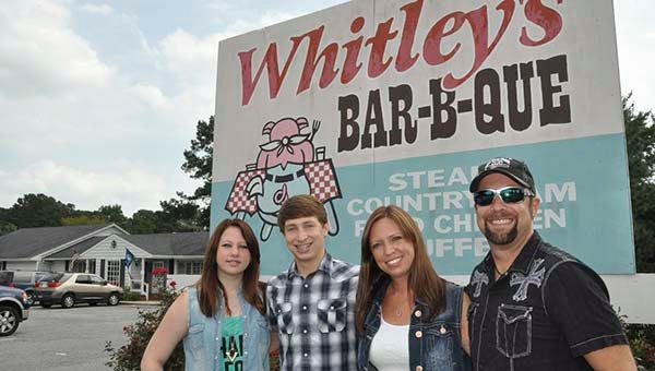 Hailey, Austin, Cassie and Colton James stand in front of the timehonored sign of tradition promoting pit-cooked Bar-B-Que at Whitley’s Bar-B-Que. -- Jim Hart | The Tidewater News