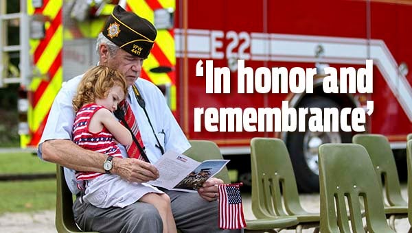 Grandfather Tim Cormany of Franklin and Leilani Scott look at the program before Post 4411’s 9/11 ceremony -- Cain Madden | Tidewater News