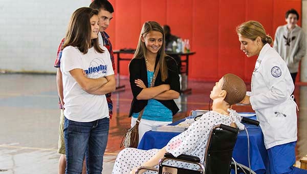 Carol Wright with PDCCC Nursing talks about healthcare to Maddie Simmons, 13, Chloe Worrell, 13, and T.J. Britt, 13, over a practice dummy. -- CAIN MADDEN | THE TIDEWATER NEWS