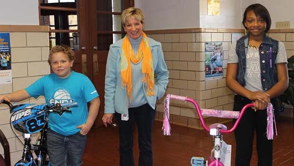 Capron Elementary Principal Dr. Allison Francis, center, presents fifth-graders Ryan Meyer-White and Lanish Givens with their brand new bikes. -- SUBMITTED
