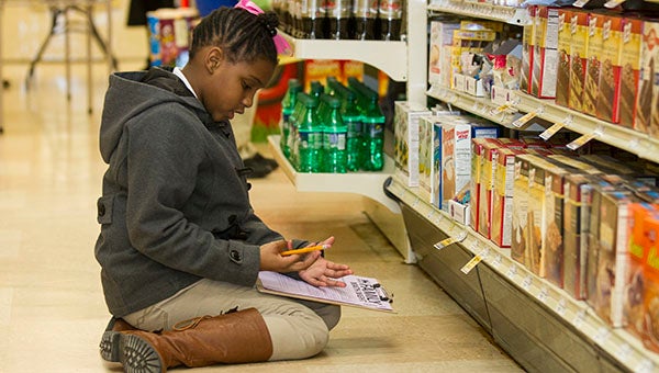 Taniyah Benn, 10, adds up some of the items in her chart on her fingers. The fifth grader needed to make sure that she had enough room left in her budget to buy cake.