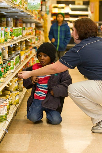 Food Lion Produce Department Manager Lisa Roth steps into the canned food aisle to help Joshua Myers, 4, a bright starts student, with finding Guiding Stars items.