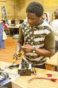 Jatrez Foster, 15, works on modifying the charger to take the robot’s battery. -- Cain Madden | Tidewater News