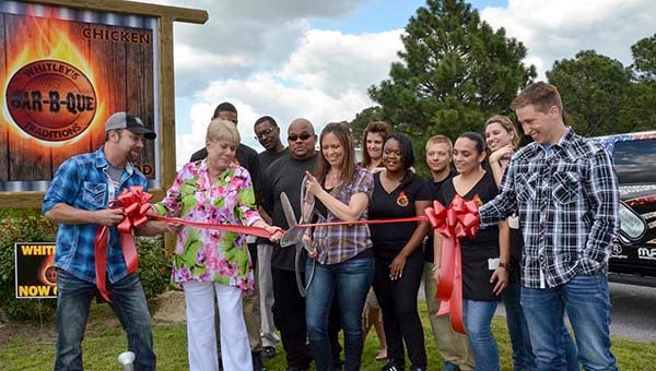 Colton James on the far left, along with Judy Hachey, and Austin James on the far right, assist Cassie James, who is holding the scissors in the ribbon-cutting ceremony at Whitley’s Bar-B-Que. -- Jim Hart | Tidewater News