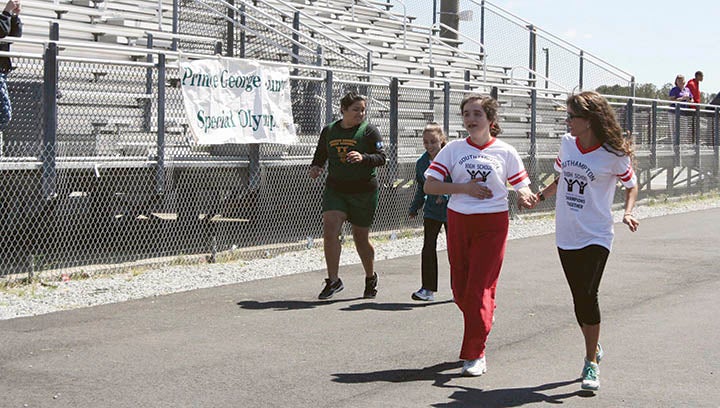 Southampton High School student Kaitlyn Thompson finishes the last stretch of a race in the Special Olympics. She is assisted by senior Katie Caulder.
