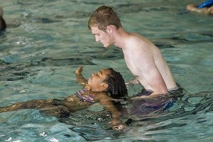 A YMCA Volunteer helps Samirah Boyd float on her back. -- Cain Madden | Tidewater News
