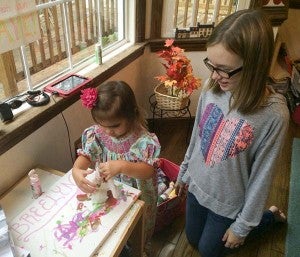 Madelyn Cosby, right, watches as Breelyn Hewett works on her own art project. Madelyn will again be auctioning off her own artwork, with the money raised to help Breelyn’s parents pay for the surgeries that their daughter has needed. -- Stephen H. Cowles | Tidewater News