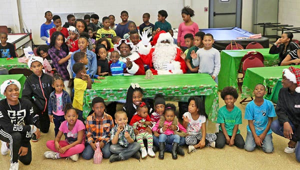 Mrs. Claus and Santa pose with the children before milk and cookies are served at the Dr. Martin Luther King Jr. Recreation Center. The annual Candy Crush took place on Saturday. -- Frank Davis | Tidewater News