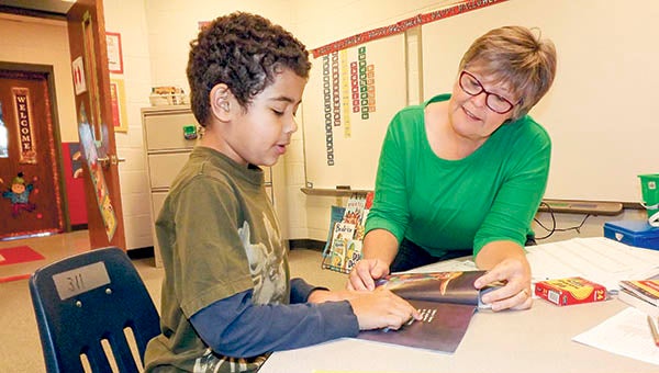 Ralphie Elliott, 7, of Riverdale Elementary School, reads a book with the help of Carolyn Lowe. The Virginia Board of Education granted Riverdale the status of being a partially accredited reconstituted school. The others are S.P. Morton Elementary and J.P. King Jr. Middle schools. -- FILE PHOTO