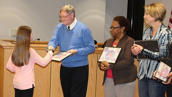 Students from S.P. Morton Elementary School presented the Franklin school board with artwork they made based on the word “gratitude.” Pictured are Emily Benton presenting her artwork to school board member Bob Holt. Also pictured are members Verta Jackson and Nancy Godwin holding the artwork they had received.