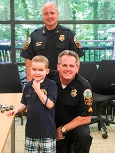 Sgt. Scott Halverson with the Franklin Police Department (kneeling right) helped make a 6 year-old-boy who has leukmia and recently had a bone marrow transplant have his dream come true by donating police memorabila which included badges, coins, cars, a shirt and several other items. -- SUBMITTED