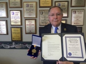 Durwood V. Scott holds up the certificate naming him as the National Association of Realtor REALTOR’s Emeritus honor. He also holds the Omega Tau Rho Medallion of Service, another national award presented for his contributions to the profession. -- Stephen H. Cowles | Tidewater News